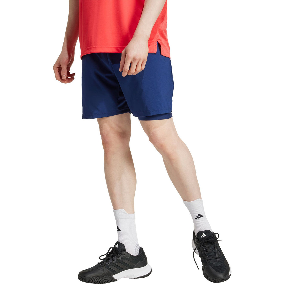 Vooraanzicht van de donkerblauwe Adidas Club 2IN1 short op model met zwarte sportschoenen