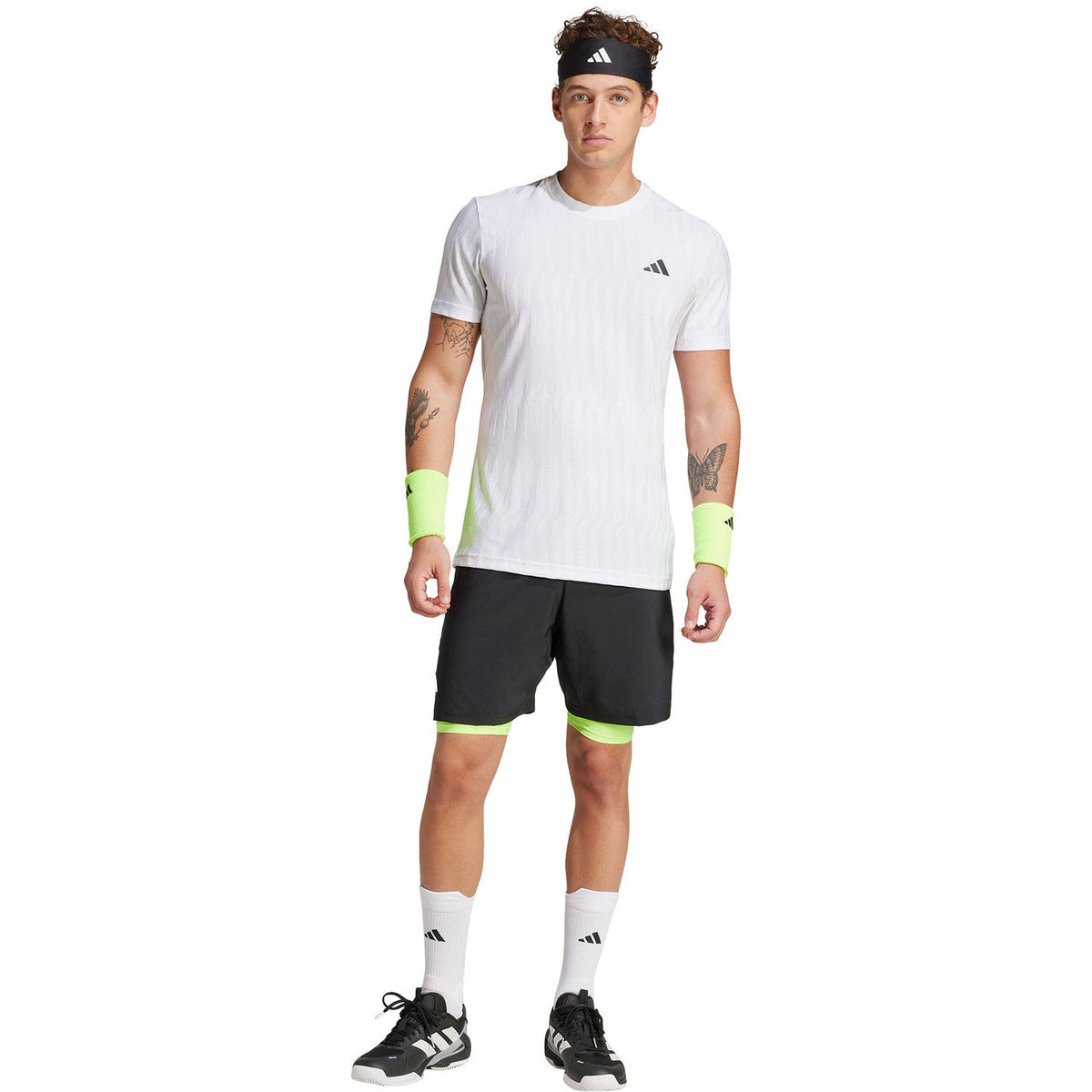 Model draagt de zwarte Adidas Club 2IN1 short met wit shirt en limegroene polsbandjes