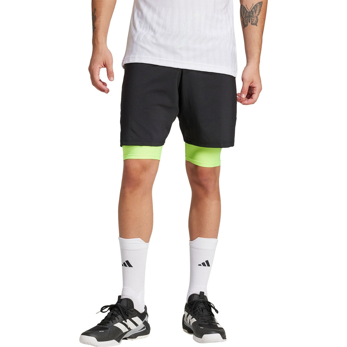 Vooraanzicht van de zwarte Adidas Club 2IN1 short met limegroene binnenbroek op model