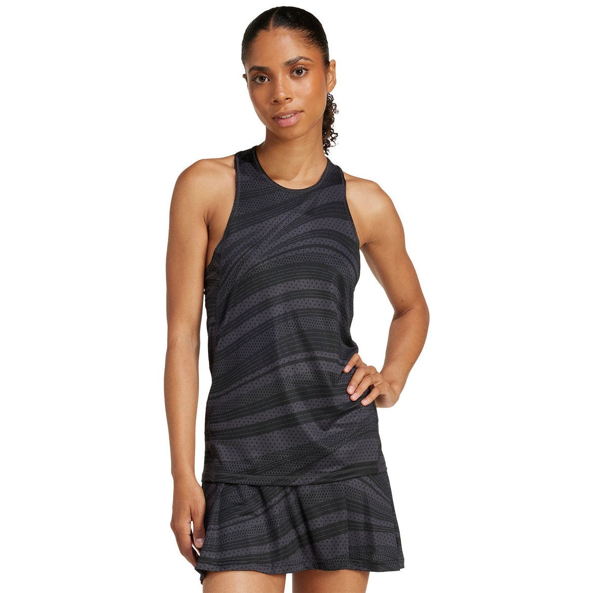 Model draagt de donkergrijze Adidas Club Graphic Tank met bijpassende plooirok