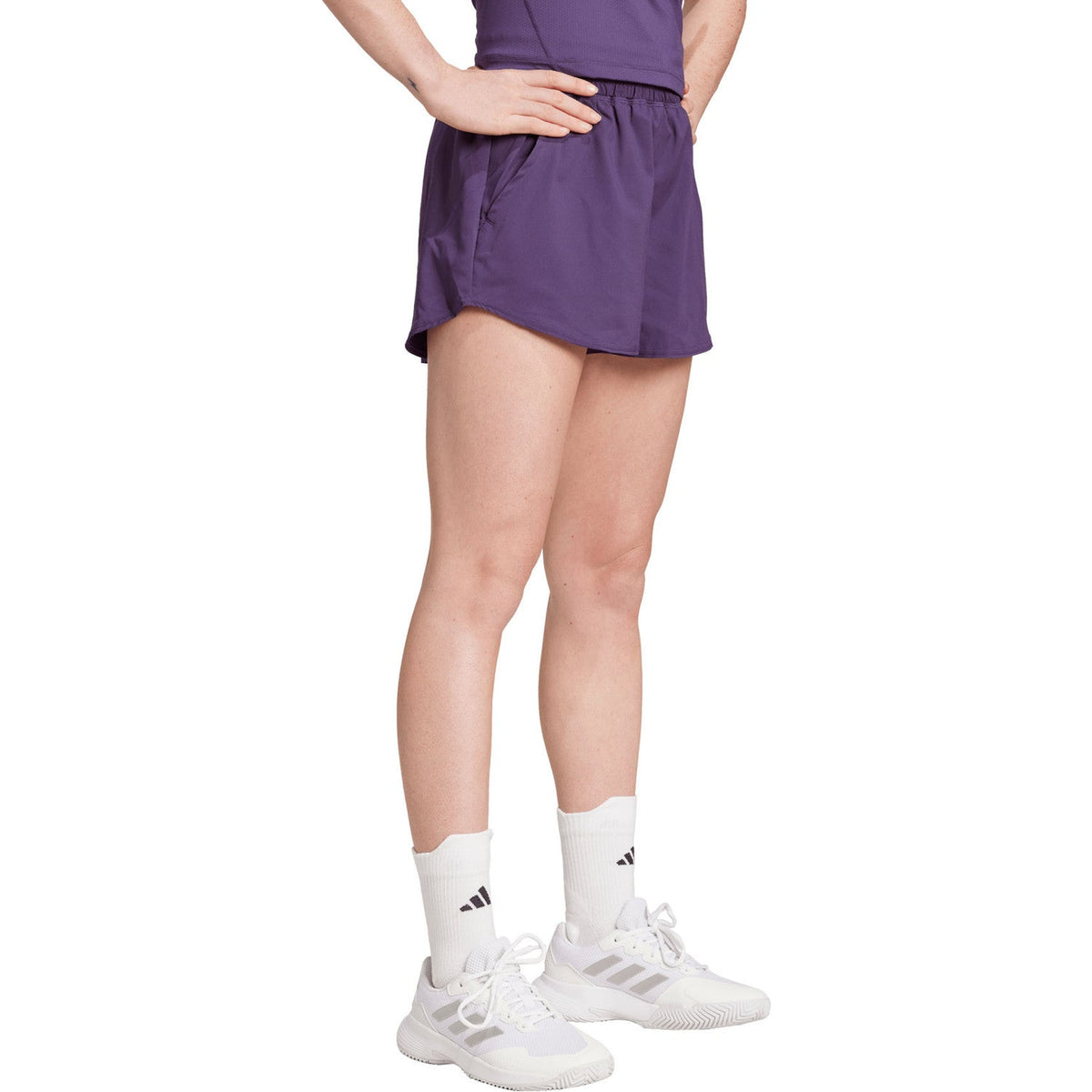 Model met hand in de zij in de paarse Adidas Club short, vooraanzicht