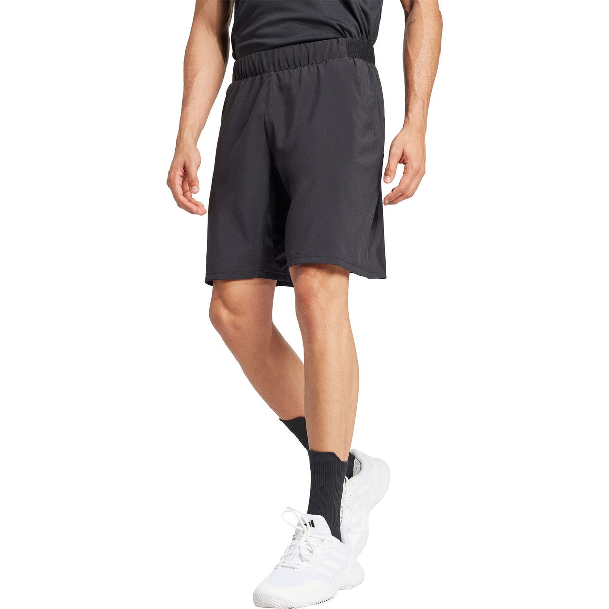 Vooraanzicht van model in de zwarte Adidas Club Stretch 9 Inch short met witte schoenen