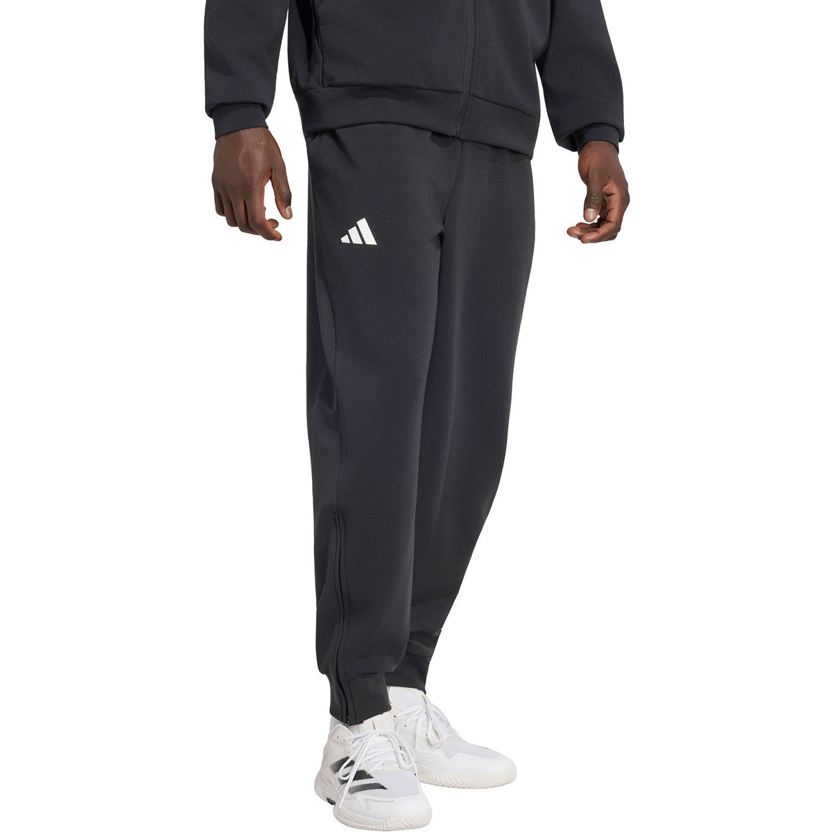Model draagt de Adidas Cover Up trainingsbroek voor heren in zwart