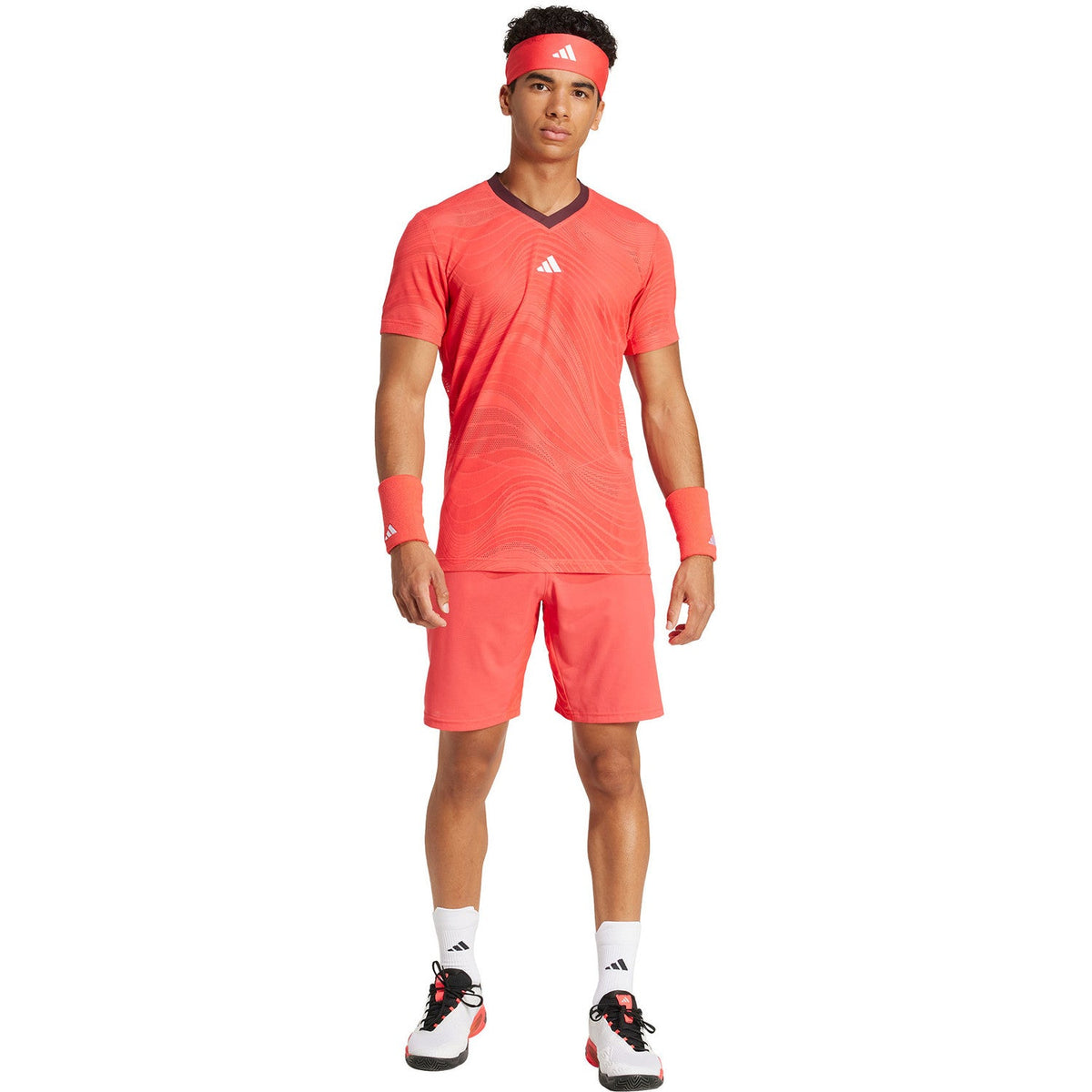 Model draagt de koraalrode Adidas Ergo short met bijpassend shirt