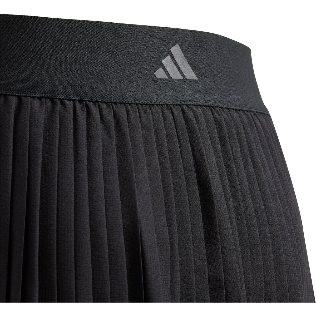 Detail van het grijze Adidas-logo op de tailleband van de zwarte Girls Club plooirok