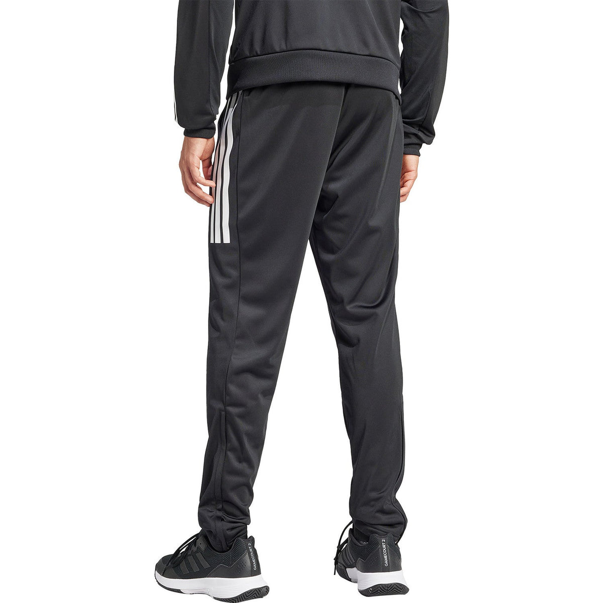 Model draagt de zwarte Adidas 3-Stripes broek met zwarte sportschoenen, vooraanzicht