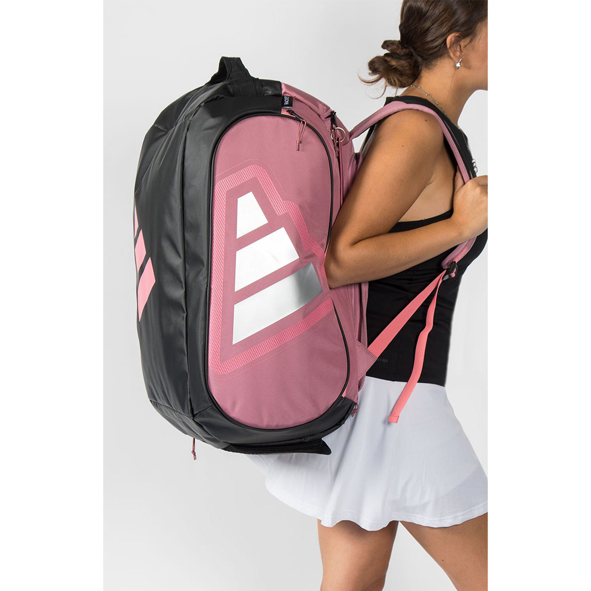 Speelster draagt de roze Adidas Protour 2026 racketbag op de rug in witte rok.