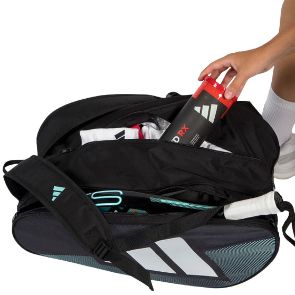 Geopende zwarte Adidas Control 2026 racketbag met rackets, bidon en grips erin.