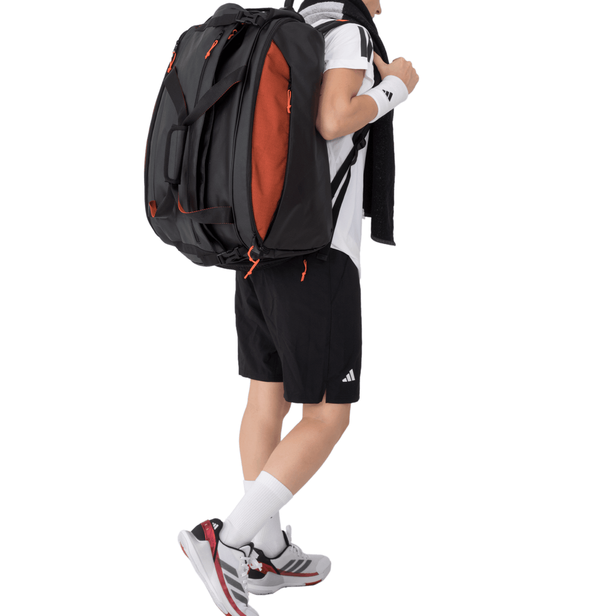 Man draagt de zwart-oranje Adidas Multigame 3.4 racketbag als rugzak met handdoek.