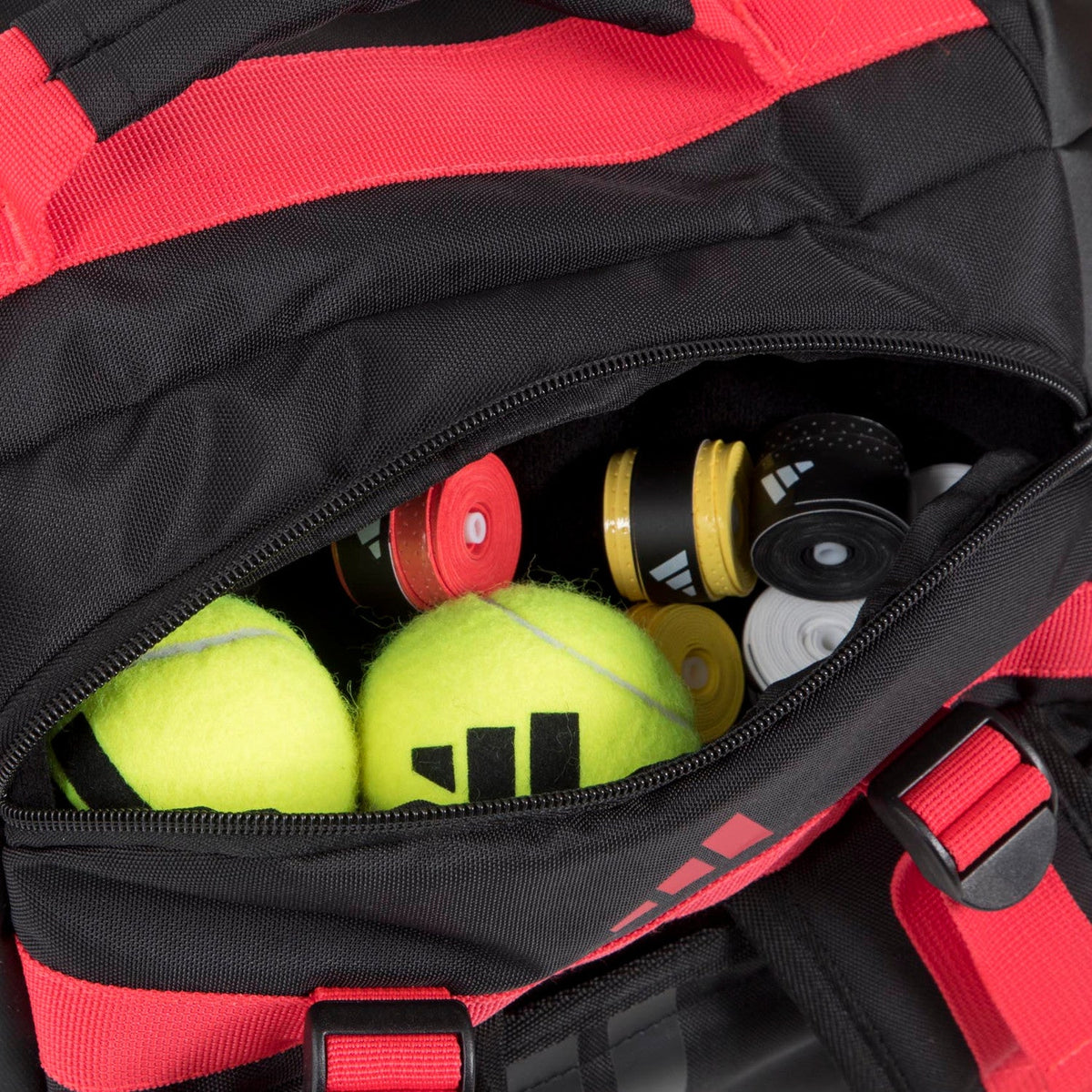 Detail van het vak van de zwart-rode Adidas Tour 3.4 met padelballen en overgrips.