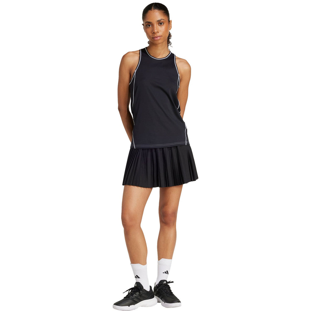 Model in volledige zwarte outfit met de Adidas Club plooirok en tanktop