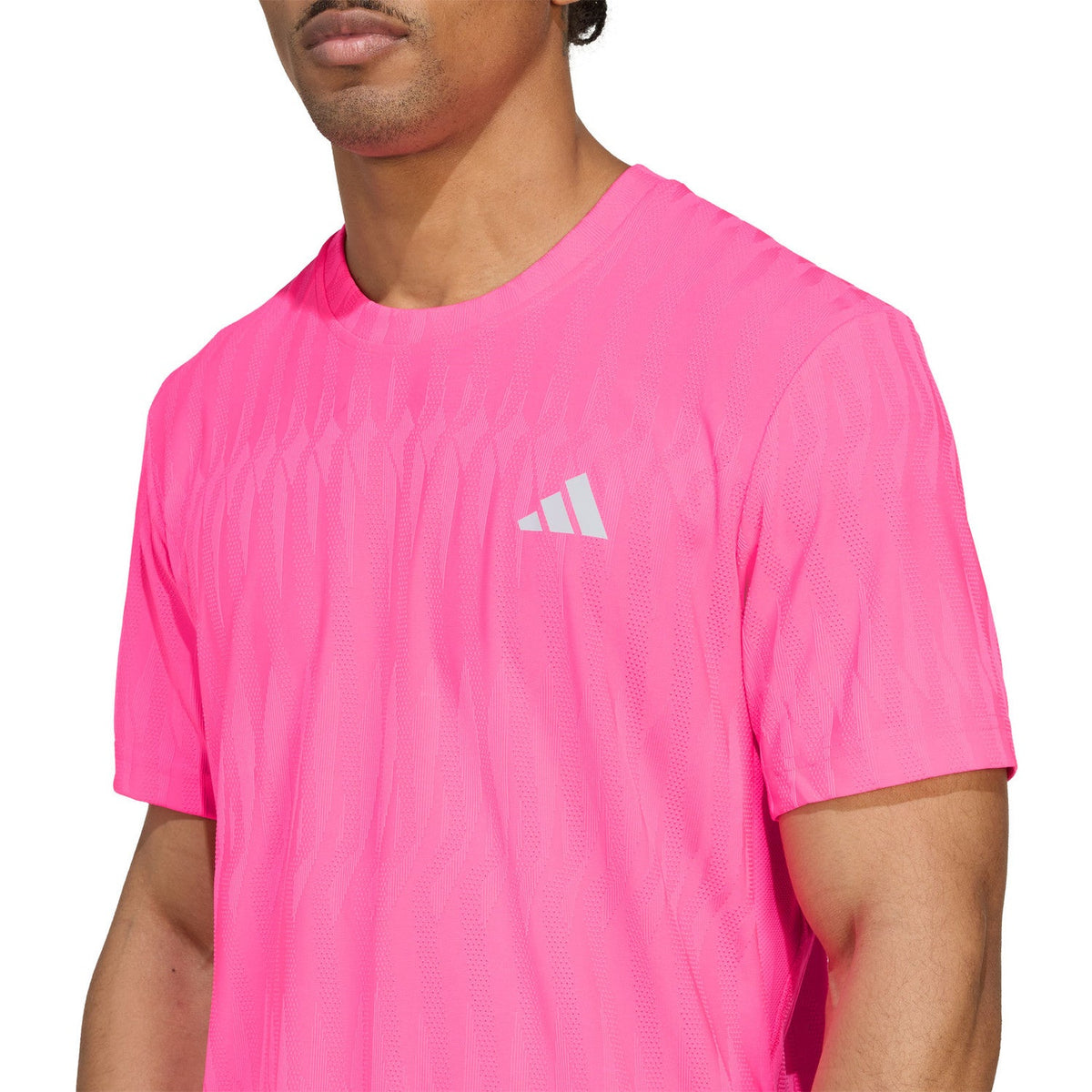 Close-up van het borstlogo op het felroze Adidas Freelift T-shirt