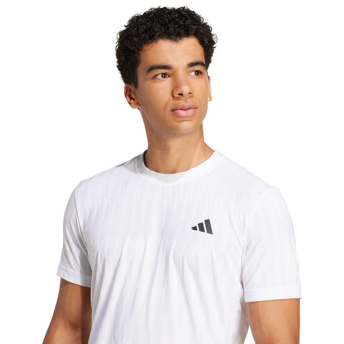 Model draagt het witte Adidas Freelift T-shirt, close-up van het zwarte borstlogo