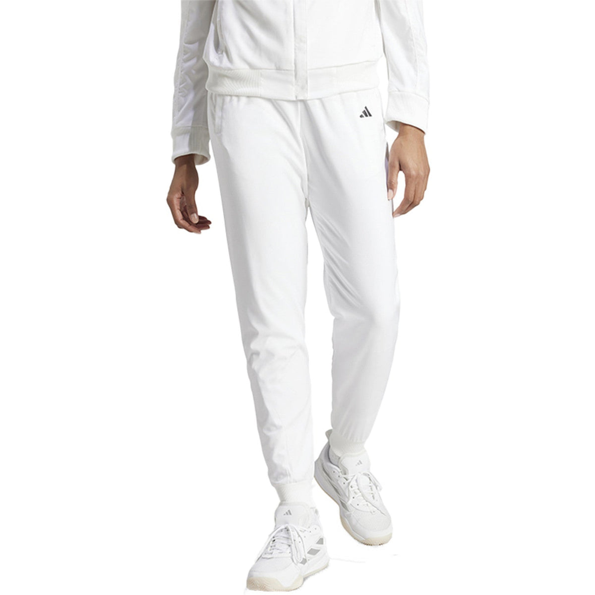 Model draagt de witte Adidas Walk On dames trainingsbroek met witte sneakers, vooraanzicht