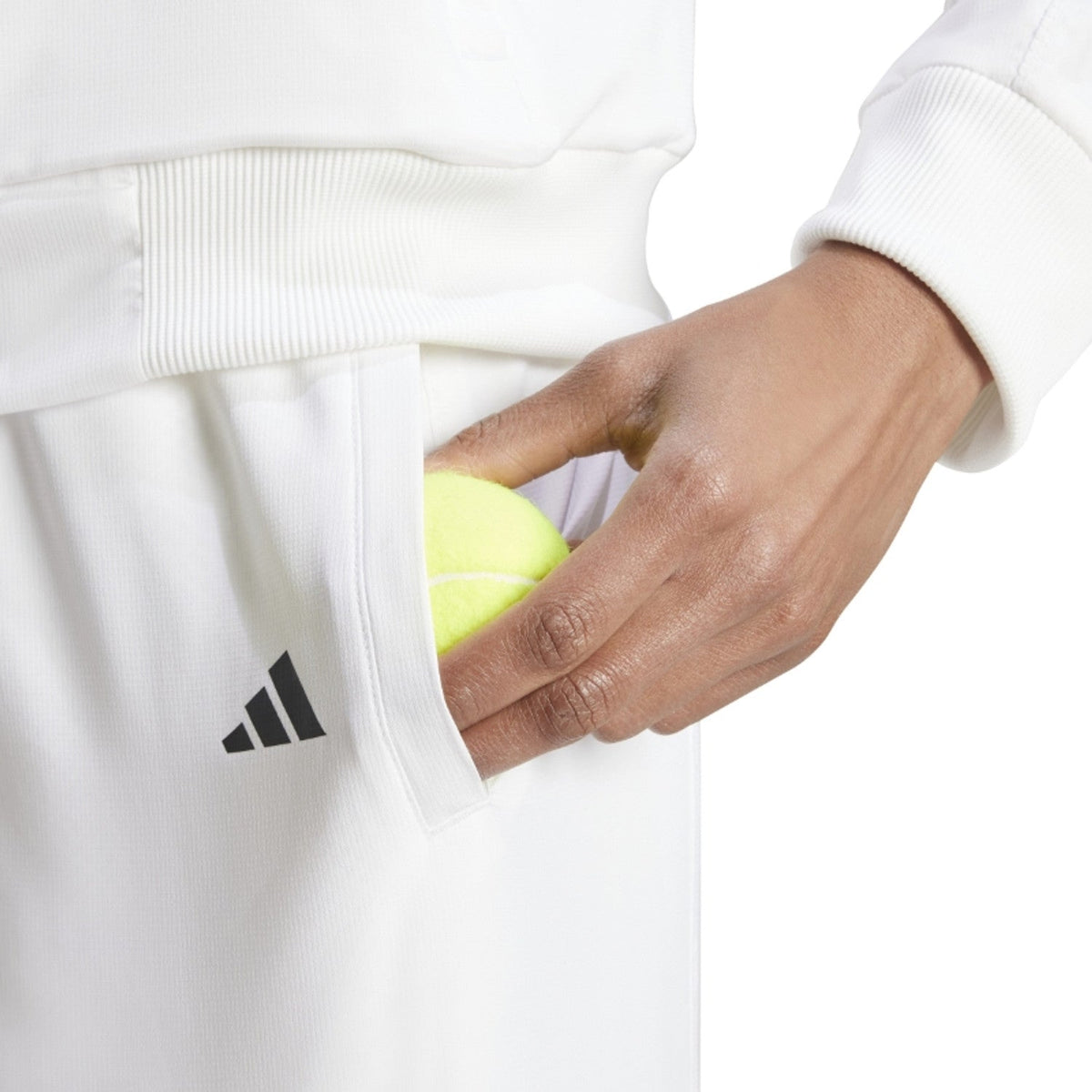 Hand stopt een gele bal in de zijzak met zwart logo van de witte Adidas Walk On broek