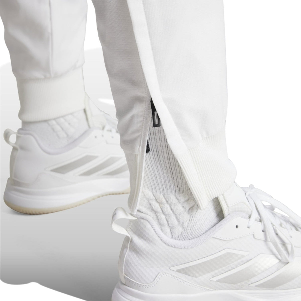 Detail van de enkelrits en boord van de witte Adidas Walk On broek boven witte sneakers