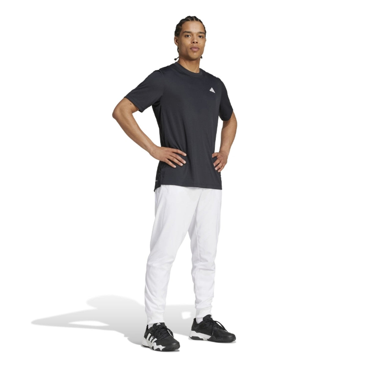 Model ten voeten uit in de witte Adidas Walk On broek met zwart Adidas shirt en zwarte sneakers