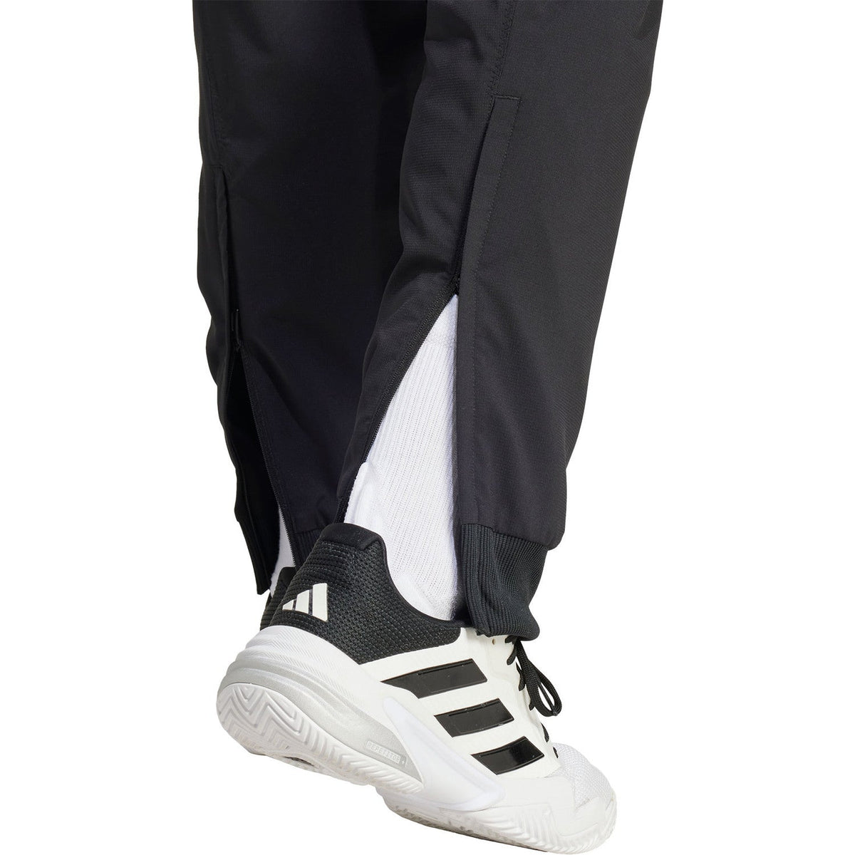 Detail van de witte inzet onderaan de pijp van de zwarte Adidas Walk On broek bij de enkel