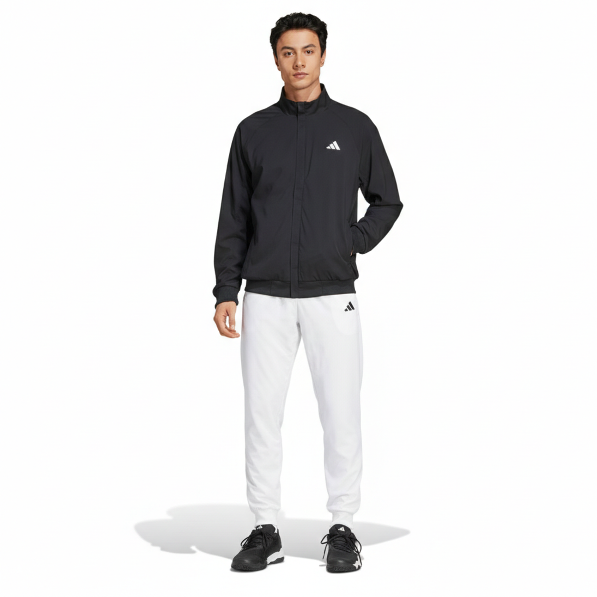 Model ten voeten uit in zwart Adidas Walk On jack en witte trainingsbroek