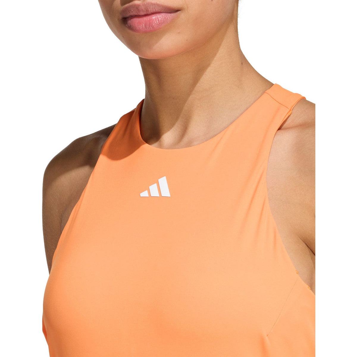 Close-up van de oranje Adidas Y-Tank met wit adidas-logo op de borst