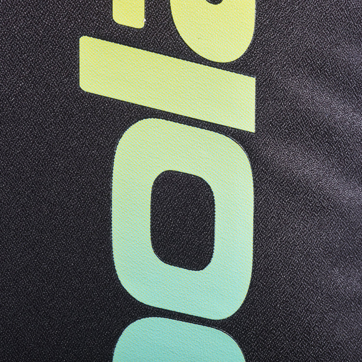 Close-up van het geel naar mintgroen verlopende Babolat logo op zwart weefsel.