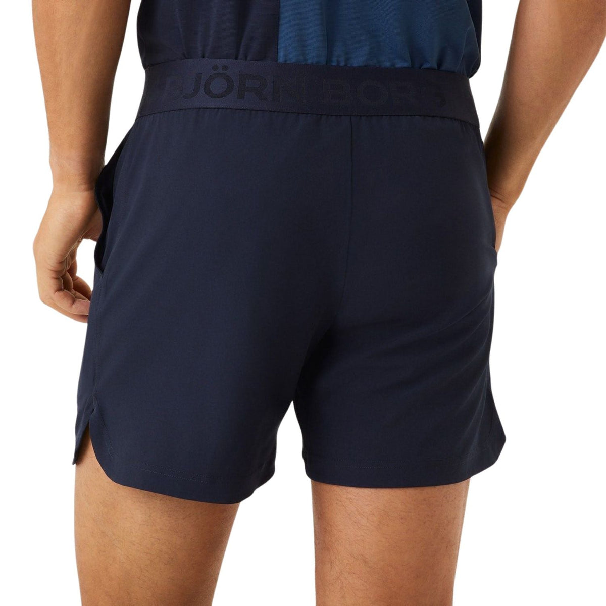 Modellen bär de mörkblå Bjorn Borg Ace-shorts, sidovy med slits i benet
