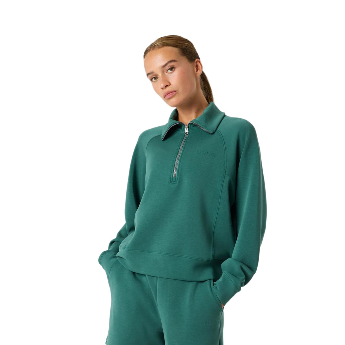 Model draagt de groene Bjorn Borg Studio Soft Halfzip sweater met bijpassende broek