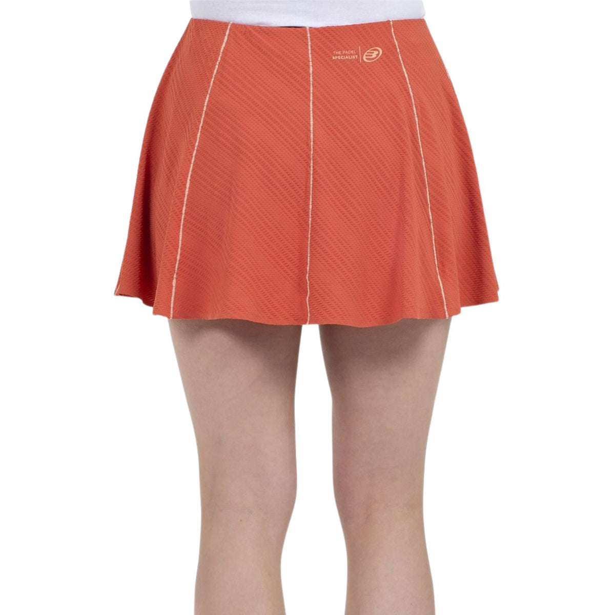 Model draagt de oranje Bullpadel Skirt Araya met klein logo op de tailleband