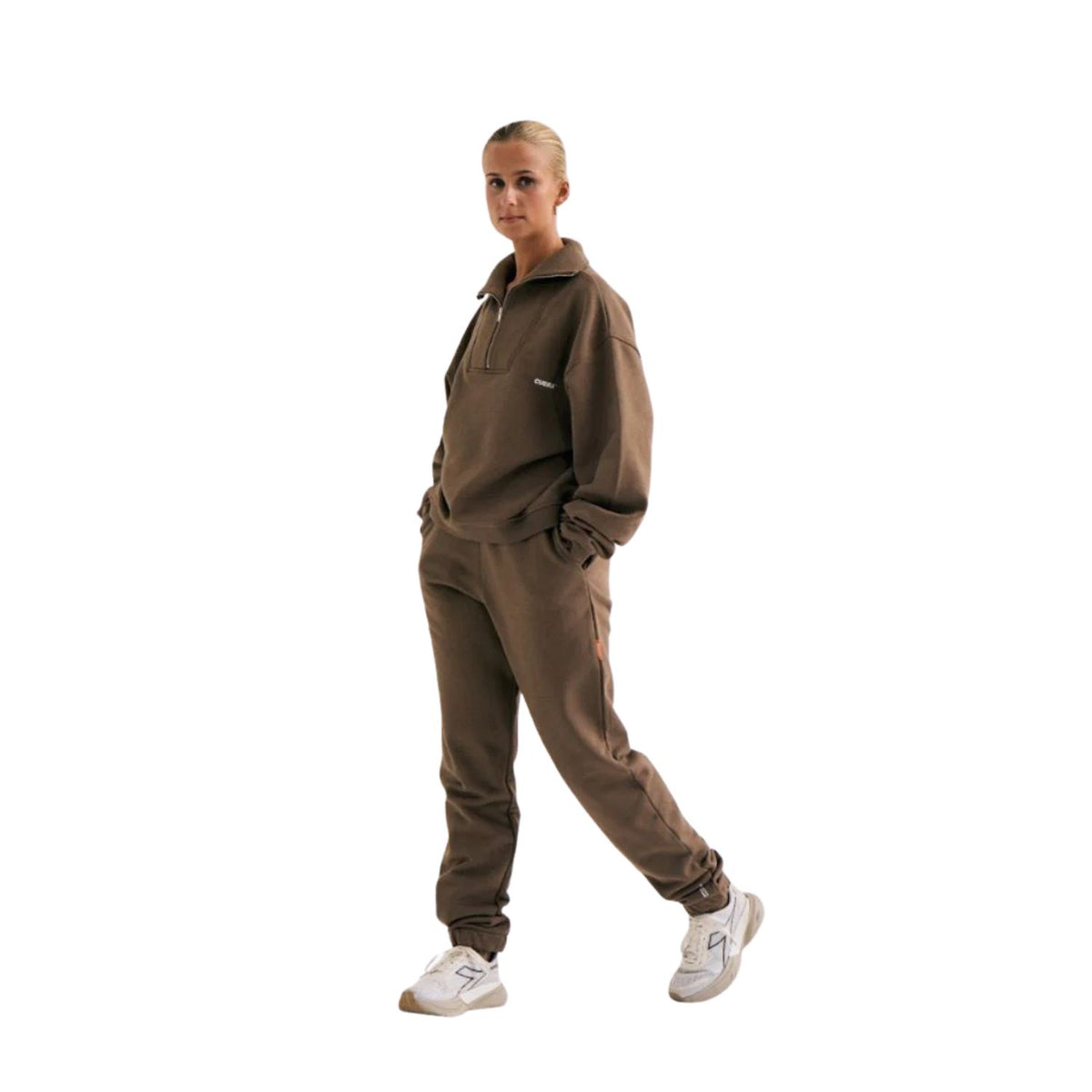 Model draagt de bruine Cuera Offcourt sweater met halve rits en bijpassende joggingbroek