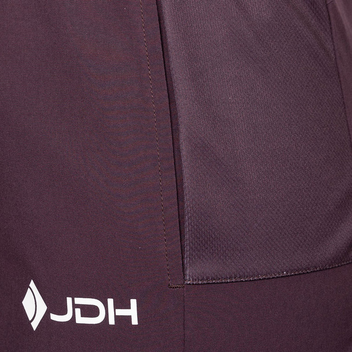Detail van de zijzak en het JDH-logo van de aubergine Performance short