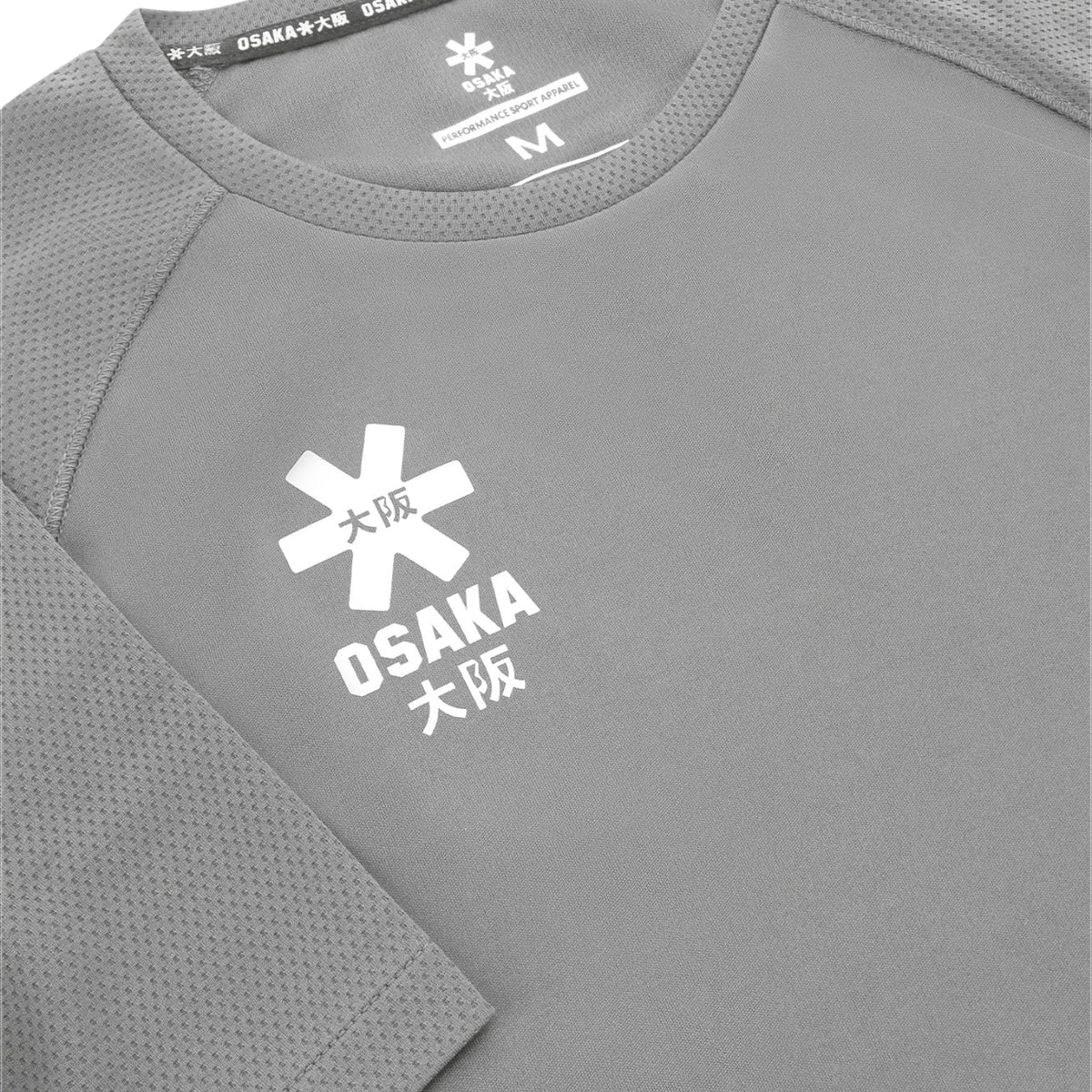 Detail van het Osaka-logo en de meshstof van het grijze Training T-shirt