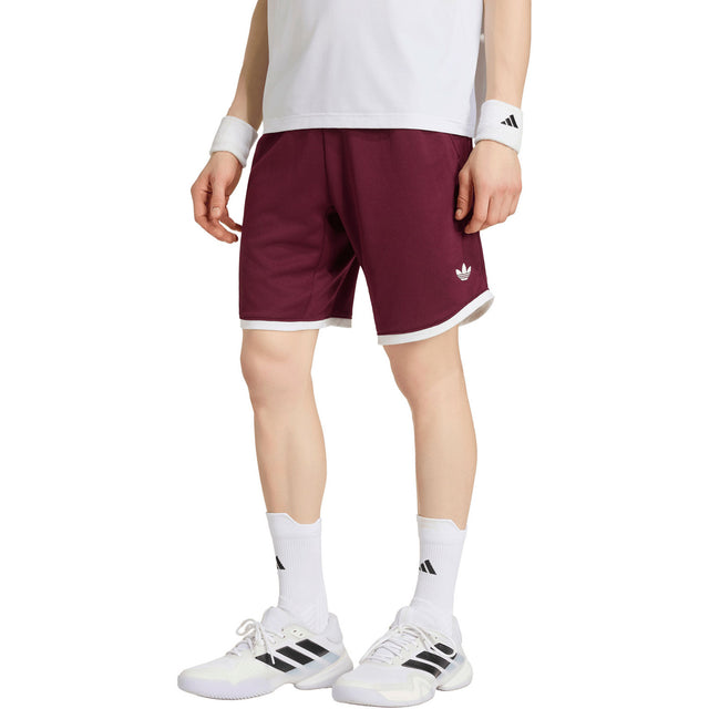 Model draagt de bordeauxrode Adidas Classics short met witte bies, vooraanzicht