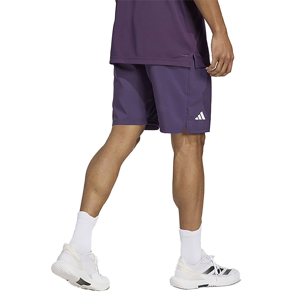 Model draagt de donkerpaarse Adidas Club 3-Stripes short, zijaanzicht met logo