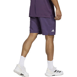 Model draagt de donkerpaarse Adidas Club 3-Stripes short, zijaanzicht met logo