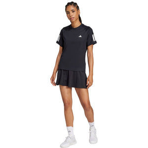 Model in volledige outfit met het zwarte Adidas Club T-shirt en zwarte plooirok