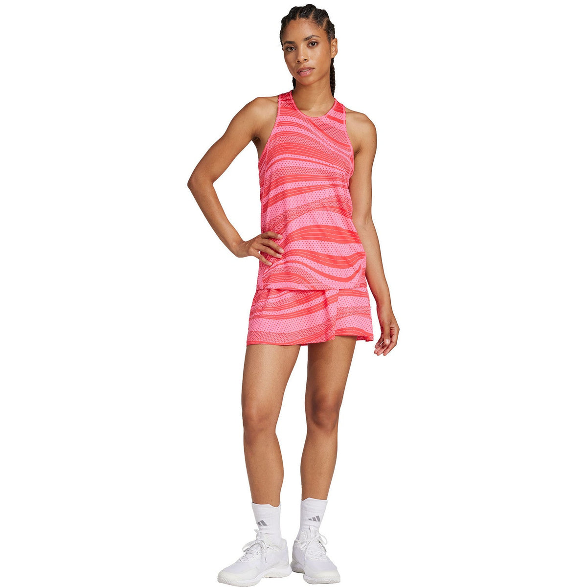 Model draagt de roze Adidas Club Graphic Tank met bijpassende rok, hand in de zij