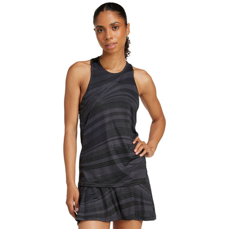 Model draagt de donkergrijze Adidas Club Graphic Tank met bijpassende plooirok