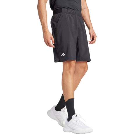 Zijaanzicht van model in de zwarte Adidas Club Stretch short met wit logo op de pijp