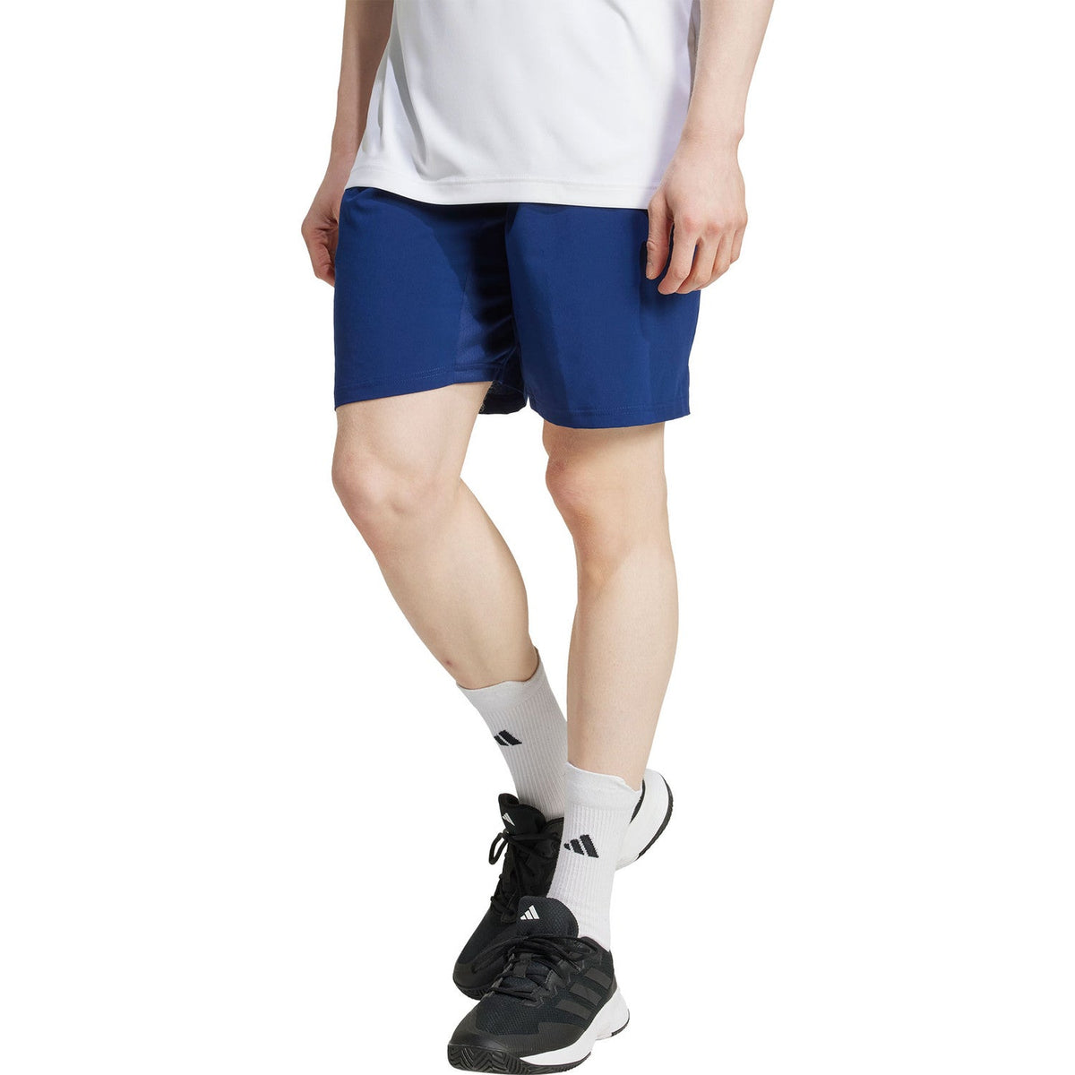 Zijaanzicht van model in de donkerblauwe Adidas Club Stretch 9 Inch short op de baan