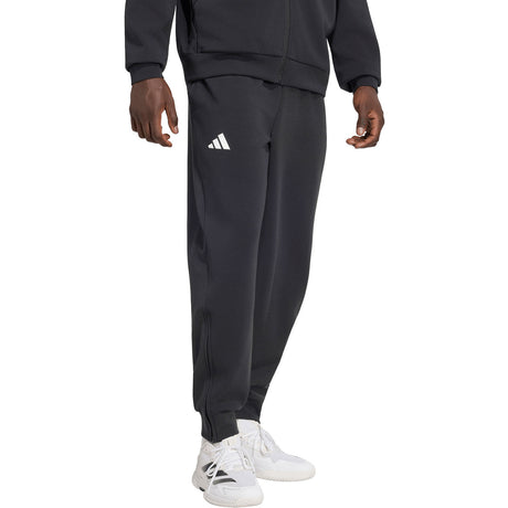 Model draagt de Adidas Cover Up trainingsbroek voor heren in zwart