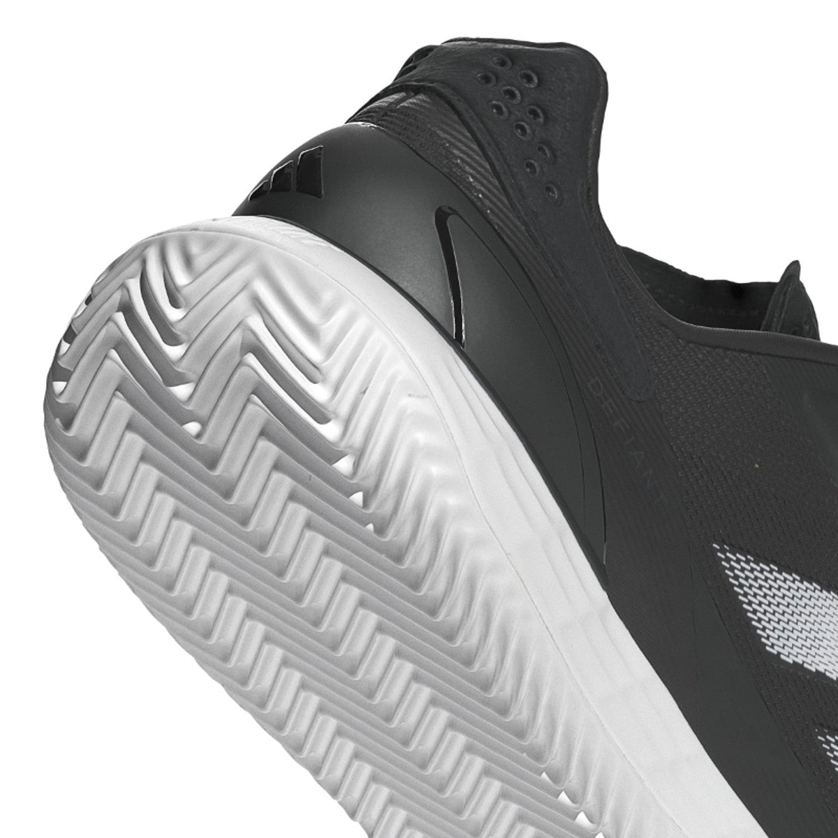 Close-up van het witte visgraatprofiel onder de zwarte Adidas Defiant Speed M
