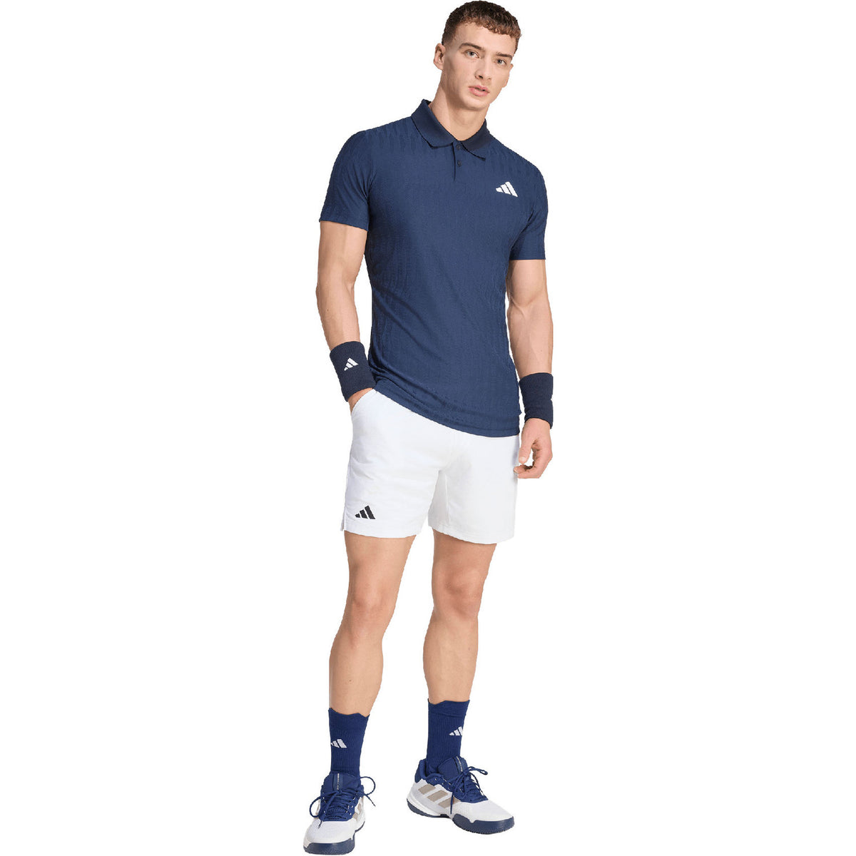Model ten voeten uit in de donkerblauwe Adidas Freelift polo en witte short