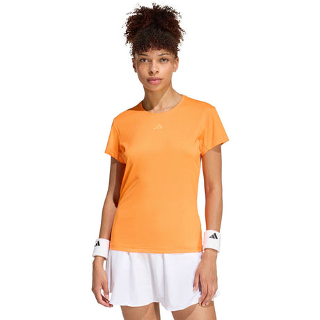 Model draagt het oranje Freelift T-shirt met witte short, vooraanzicht