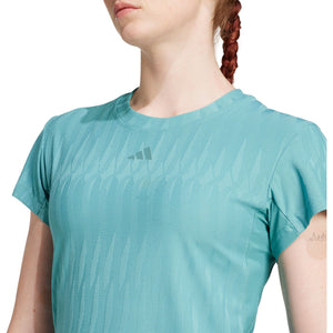Detail van het logo en de gebreide structuur van het turquoise T-shirt