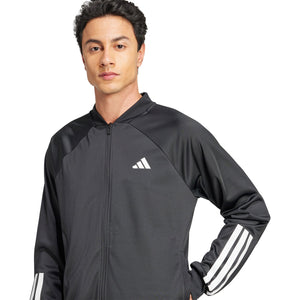 Model met hand in de zij draagt het zwarte Adidas 3-Stripes jack met wit logo