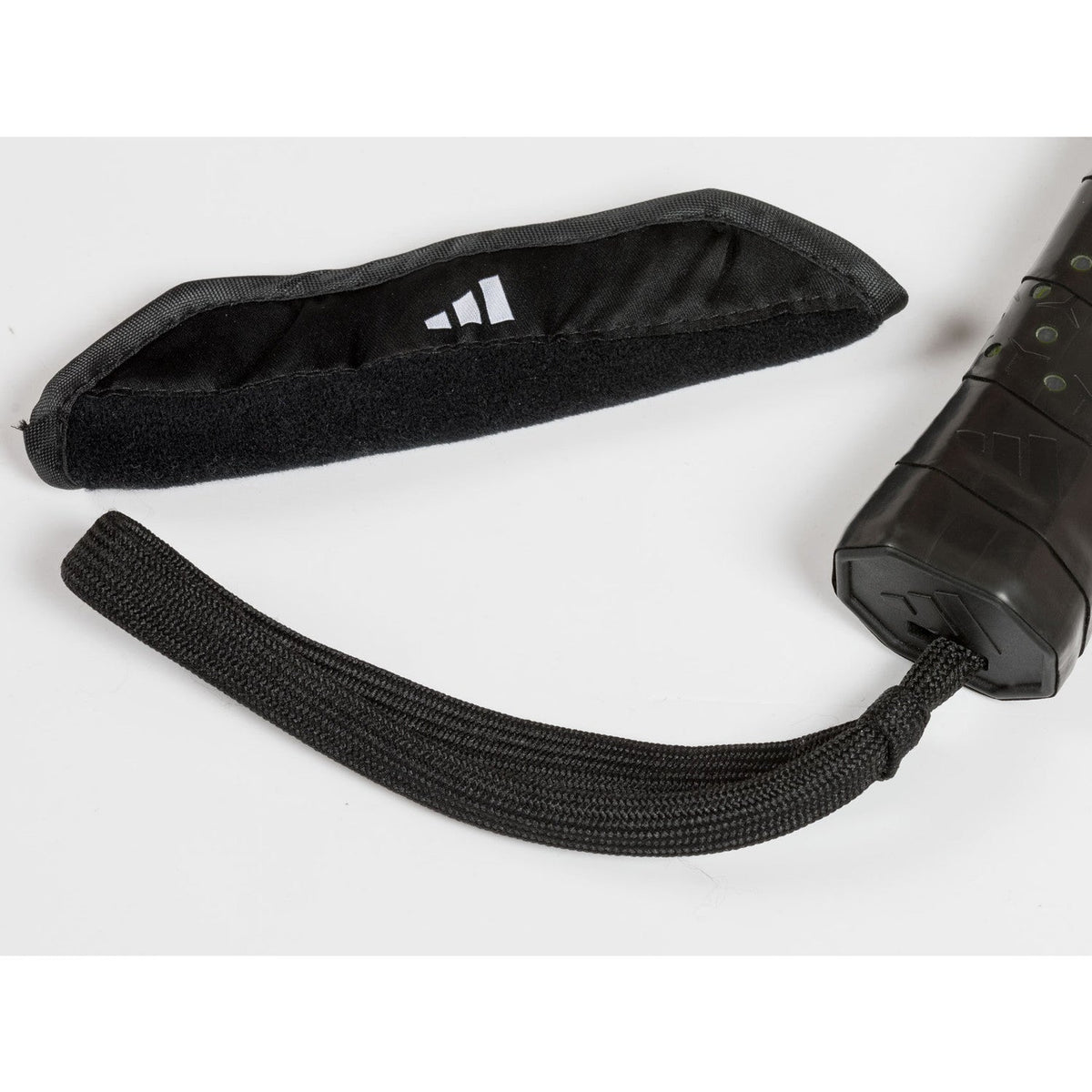 Zwarte beschermhoes en polsband van adidas naast het Adidas Metalbone 3.5 padelracket