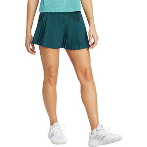 Zijaanzicht van model in de petrolgroene Adidas Pleated Skirt Pro met witte schoenen