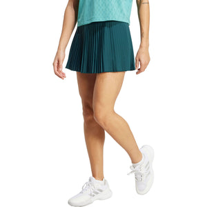 Model draagt de petrolgroene Adidas Pleated Skirt Pro met turquoise sportshirt