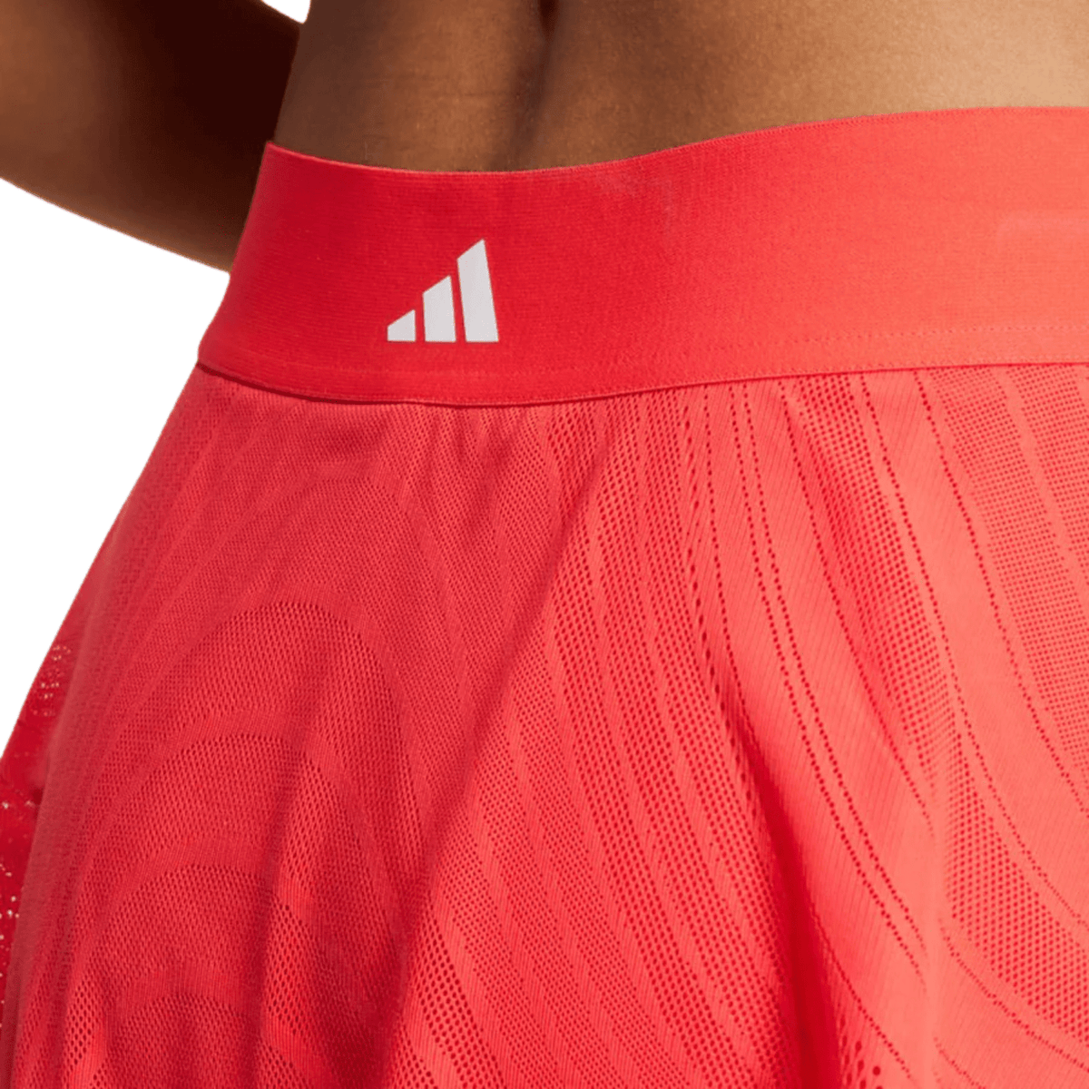 Detail van de tailleband van de koraalrode Print Skirt Pro met wit Adidas-logo