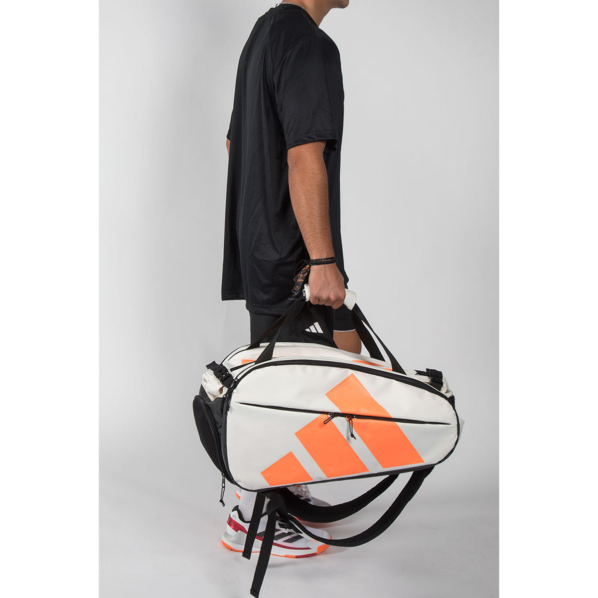 Man draagt de gebroken witte Adidas Multigame 2026 racketbag aan de schouderband.